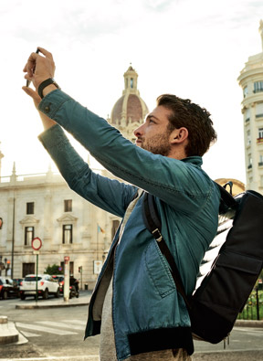 Ein Mann mit einem Rucksack auf dem Rücken macht ein Foto mit seinem Handy.