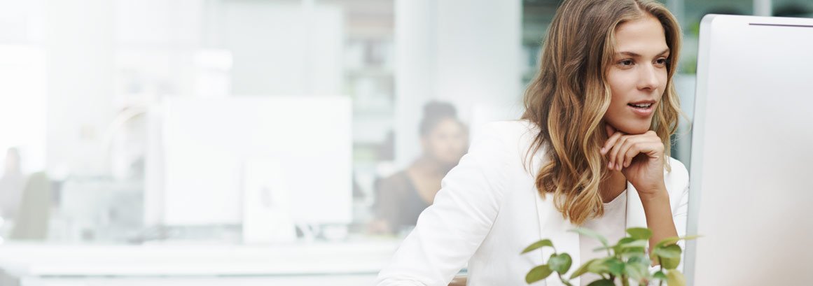 Eine Frau sitzt konzentriert vor einem Computerbildschirm