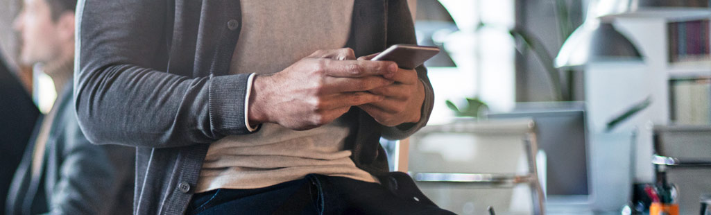 Ein Mann hält ein Handy in der Hand und prüft seine Kontakte und Termine, die er dank der Cloud immer dabei hat.