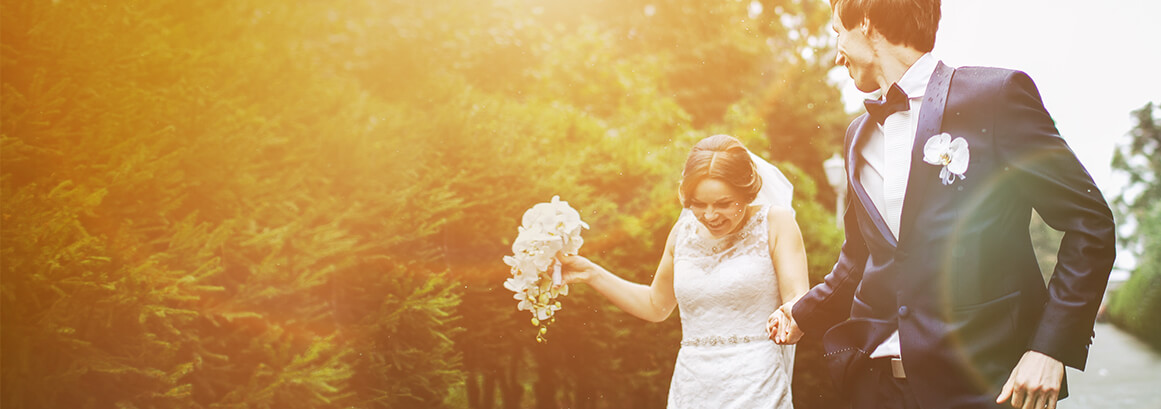 Braut und Bräutigam laufen eine Wiese entlang.
