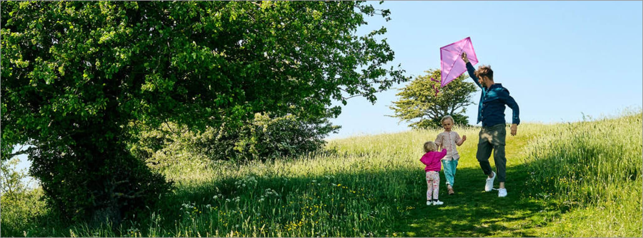 Ein Vater sitzt mit mit seinem Kind in einer Hängematte. Sie machen gemeinsam ein Selfie.